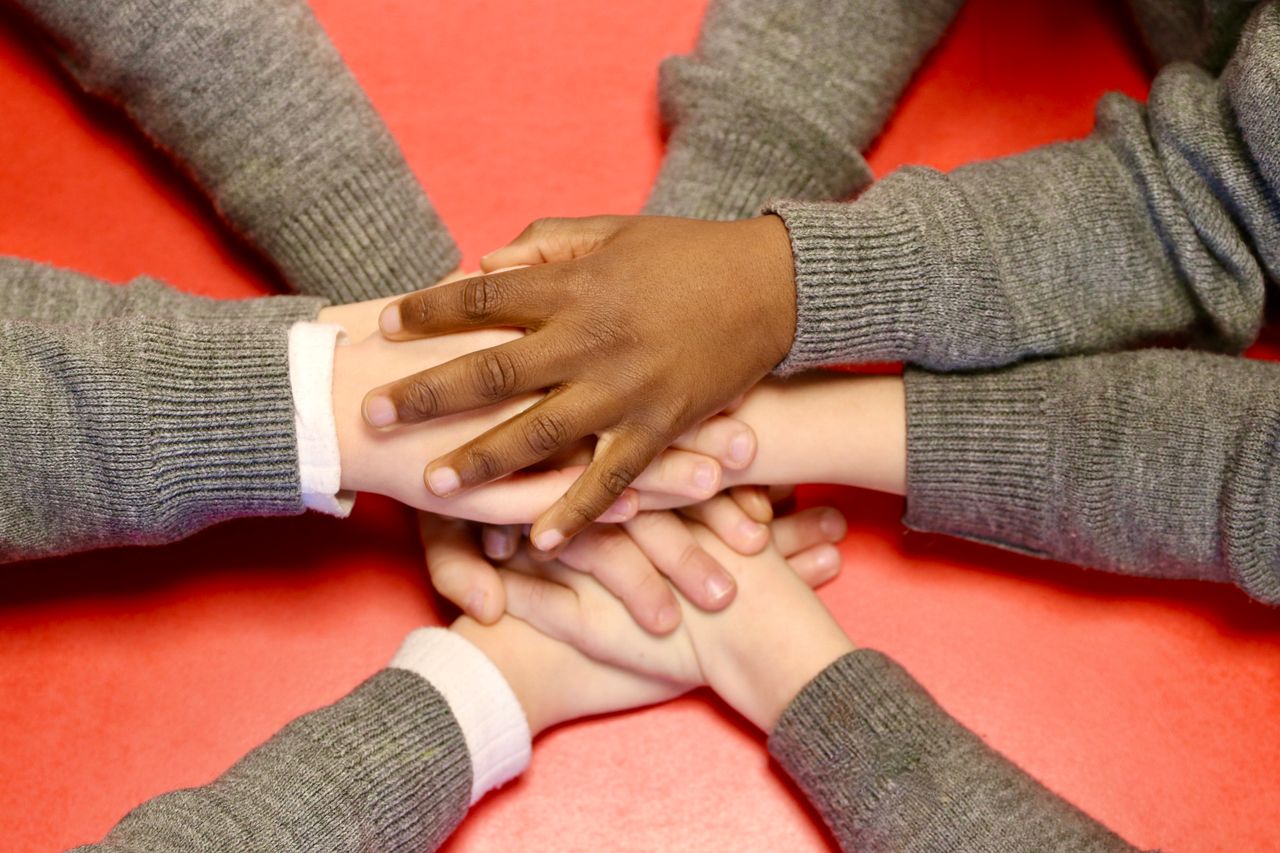 Close-up of diverse hands joining together, symbolizing teamwork, unity, and support.